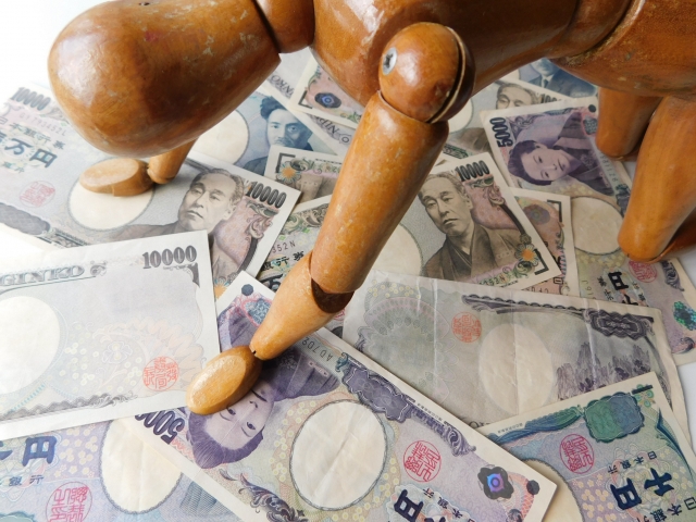 お金の上でうなだれる。新宿区で借金返済の相談は無料でできます